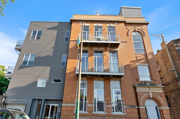 Front view of a multi-story building with brick facade and balconies.