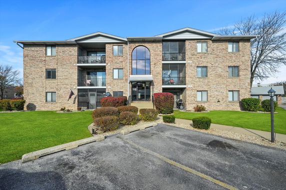 Front view of a three-story apartment building with brick facade and balconies.