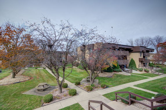 Front view of a multi-story apartment building with balconies and landscaped surroundings.