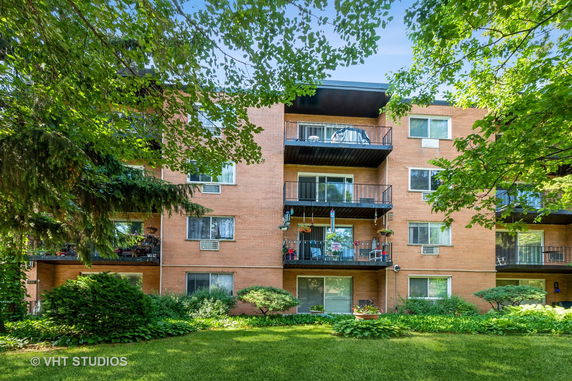 Front view of a multi-story brick apartment building with balconies.