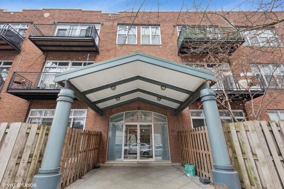 Front view of a multi-story brick building with balconies and a covered entrance.
