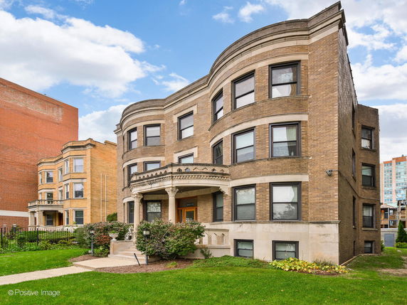 Front view of a multi-story brick building with large windows and a decorative entrance.