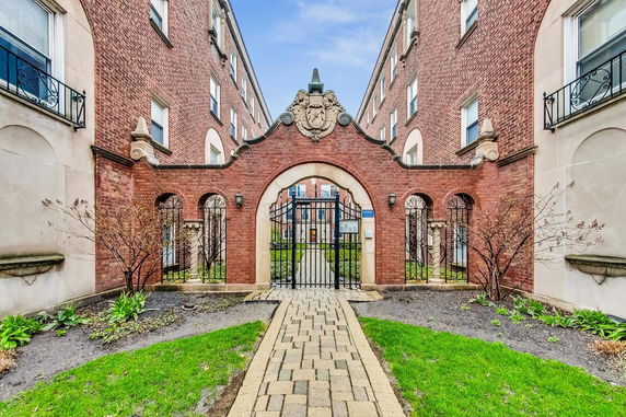Front view of a brick building with decorative arch and gate entrance.