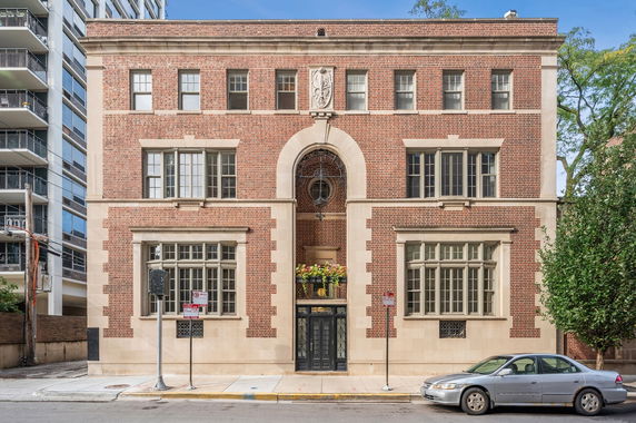 Front view of a brick building with large windows and an arched entrance.