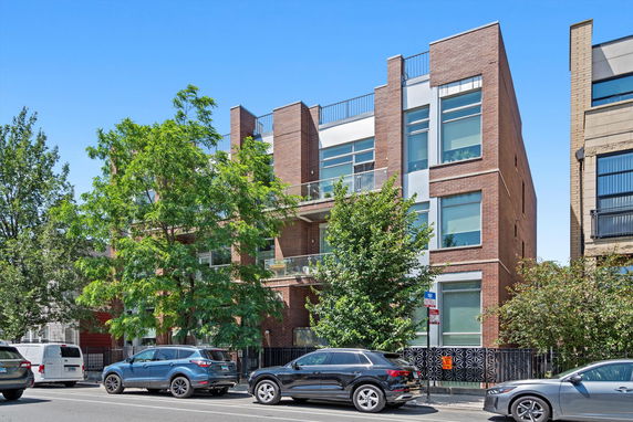 Front view of a modern multi-story building with large windows and balconies.