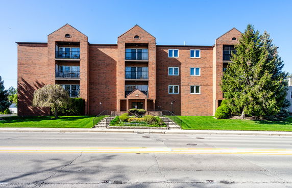 Front view of a brick multi-story apartment building with balconies.