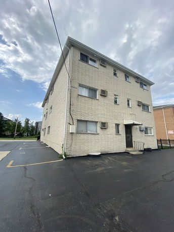 Front view of a multi-story apartment building with brick exterior.