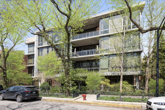 Front view of a modern multi-story apartment building with large glass windows and balconies.