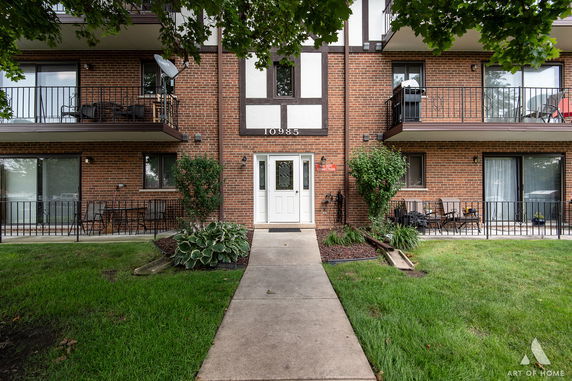 Front view of a multi-story brick apartment building with balconies.