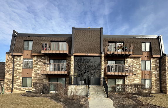 Front view of a multi-story apartment building with brick exterior and balconies.