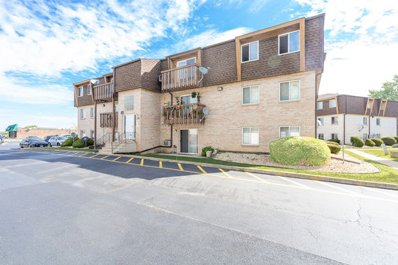 Front view of a multi-story brick apartment building with balconies.