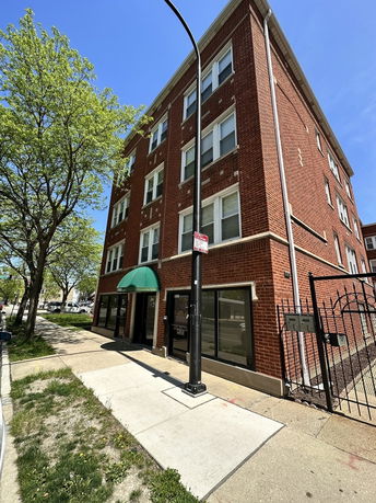Front view of a four-story brick building with multiple windows and a green awning above the entrance.