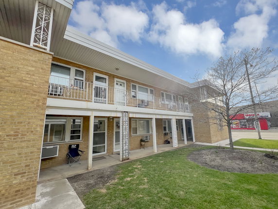 Front view of a two-story brick building with a balcony and white railings.