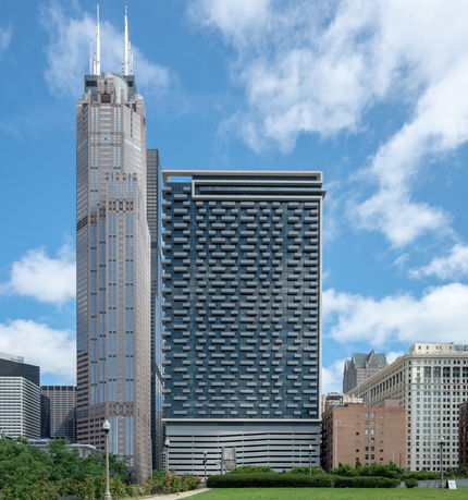 Front view of two tall modern skyscrapers with distinct architectural designs.