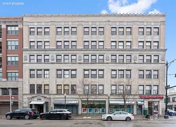 Front view of a multi-story commercial building with retail stores at the ground level.