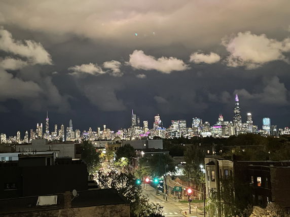 Panoramic view of a city skyline at night with illuminated buildings.