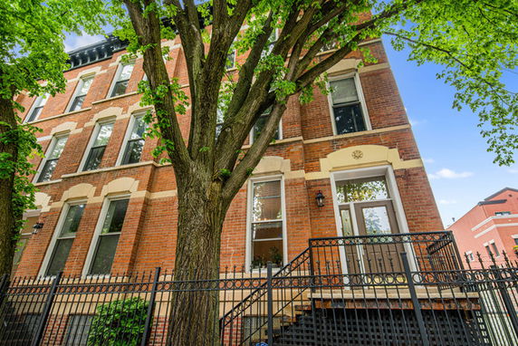 Front view of a multi-story brick building with large windows and a metal entrance staircase.
