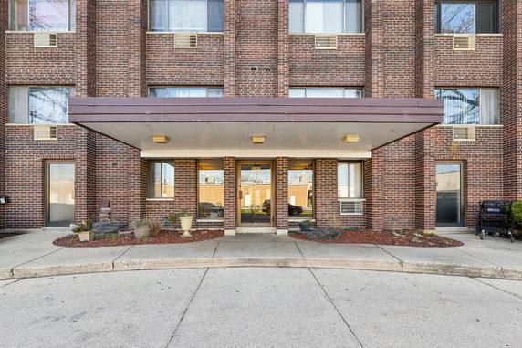 Front view of a multi-story brick building with large windows and a covered entrance.