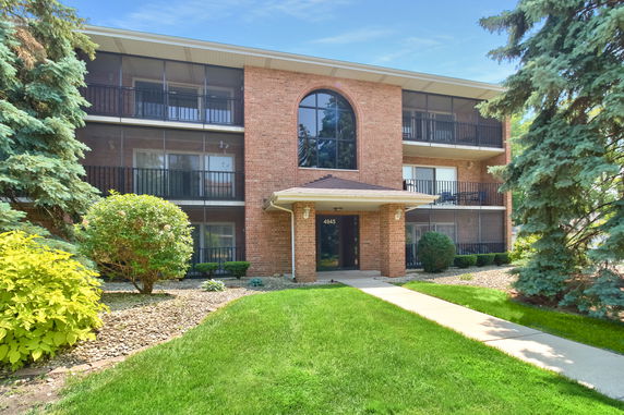 Front view of a three-story brick apartment building with balconies.