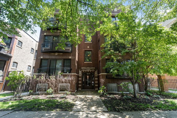 Front view of a multi-story brick apartment building with multiple balconies.