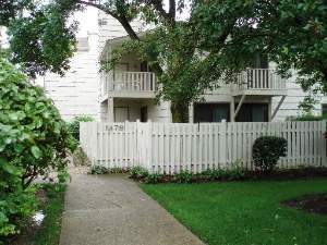 Front view of a two-story house with balconies and a white fence.