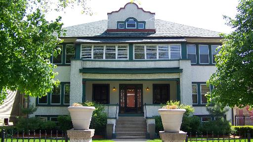 Front view of a two-story house with a decorative gable and multiple windows.