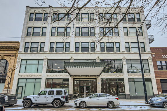 Front view of a multi-story building with large windows and decorative facade.