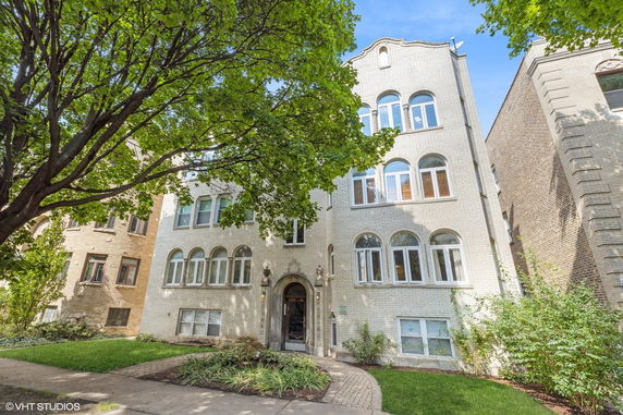 Front view of a multi-story residential building with arched windows and a decorative entrance.
