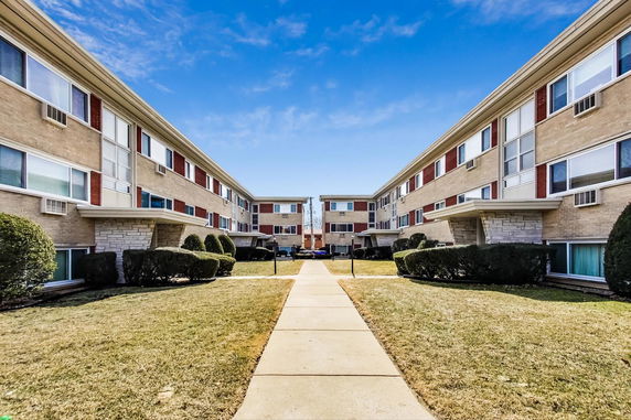 Front view of a multi-story apartment building with a central pathway.