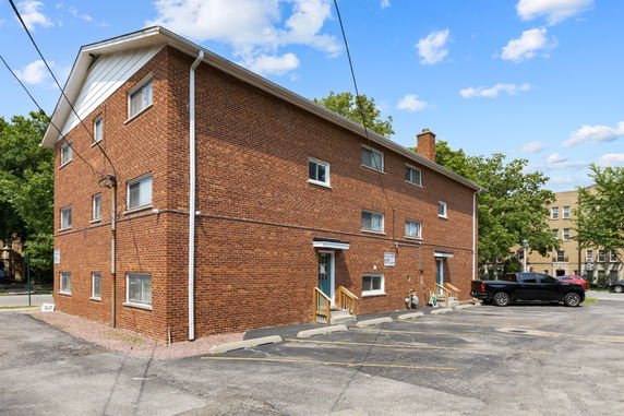 Front view of a multi-story brick building with a sloped roof and multiple windows.