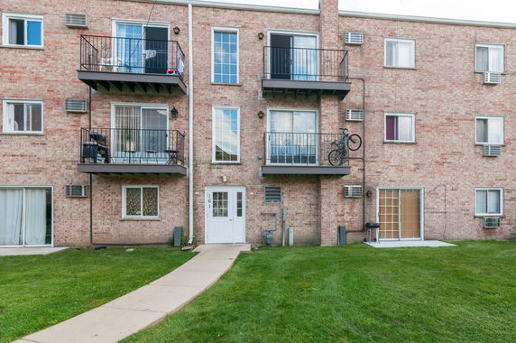 Front view of a three-story brick apartment building with balconies.