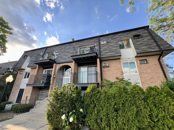 Front view of a two-story brick apartment building with balconies.
