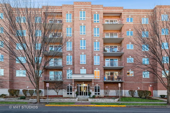 Front view of a multi-story brick apartment building with balconies.