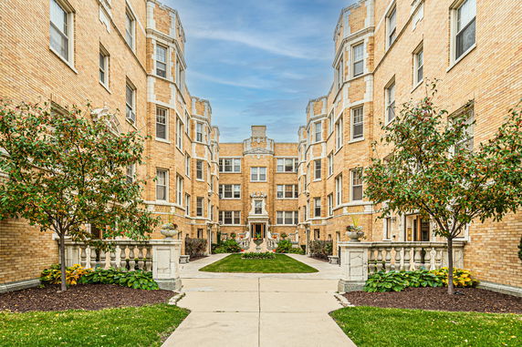Front view of a multi-story brick apartment building with decorative stone accents.