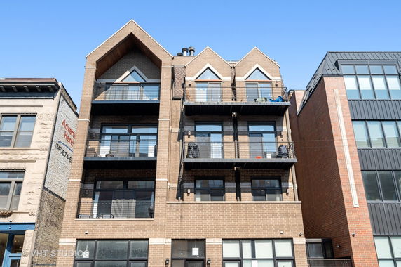 Front view of a multi-story building with balconies and brick facade.