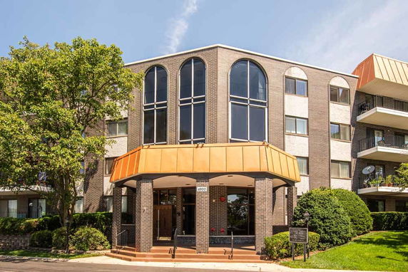 Front view of a multi-story brick building with large arched windows and an entrance canopy.