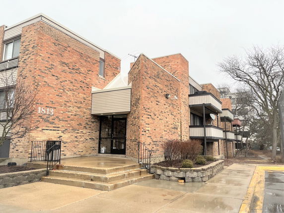 Front view of a brick apartment building with balconies and entrance steps.