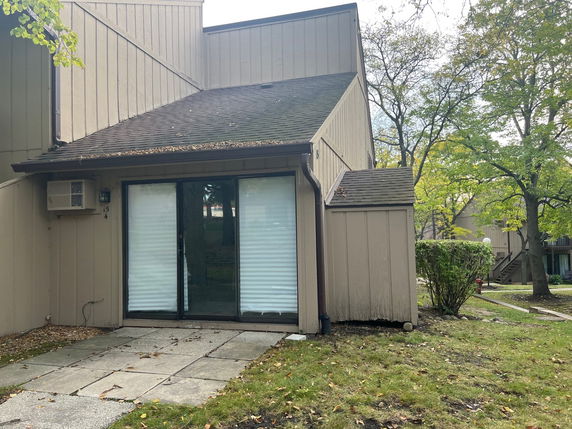 Front view of a two-story building with sliding glass door and air conditioning unit.