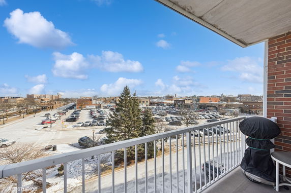 View from a balcony overlooking a parking lot and surrounding buildings.