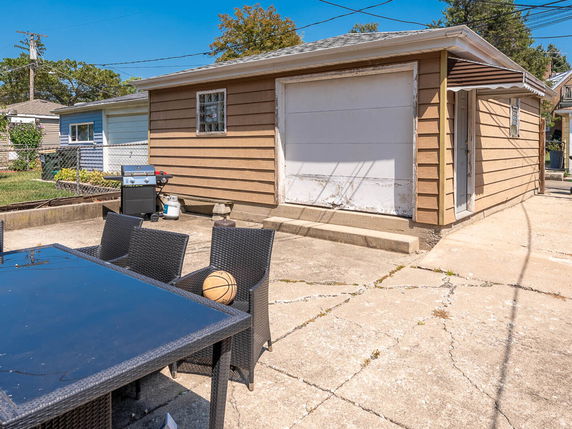 Outdoor parking area with a garage and a patio table with chairs.