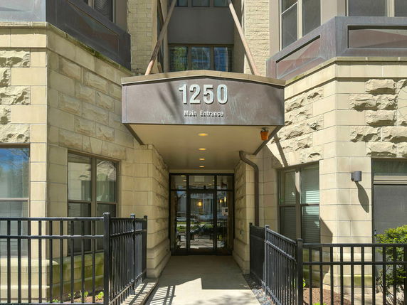 Front view of a building entrance with a stone facade and metal railing.