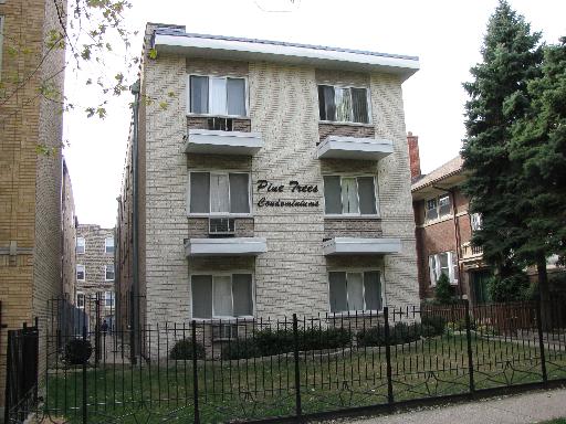 Front view of a three-story apartment building with a fenced yard.