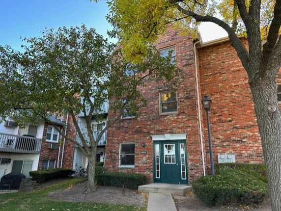 Front view of a multi-story brick building with a green door.