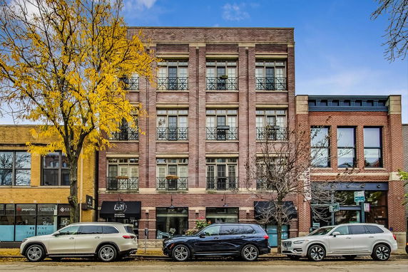Front view of a multi-story brick building with large windows.