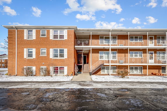 Front view of a brick apartment building with multiple levels and metal staircases.