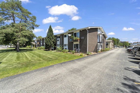 Front view of a two-story residential building with a well-maintained lawn and parking area.