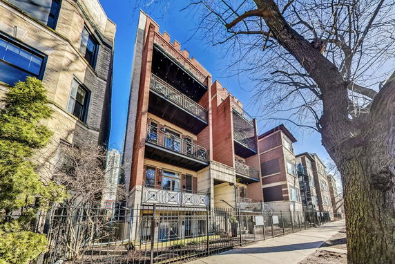 Front view of a multi-story brick apartment building with balconies.