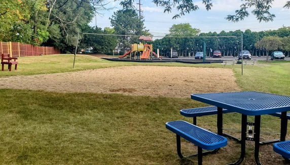 Playground area with swings, a slide, and picnic tables.
