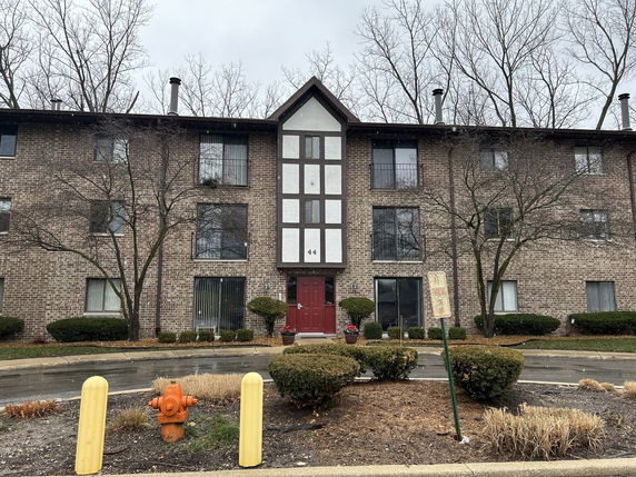 Front view of a three-story brick apartment building with central entrance.