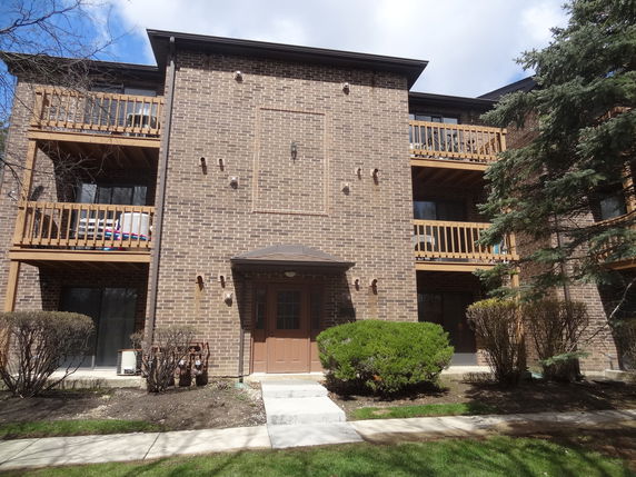 Front view of a three-story brick apartment building with balconies.